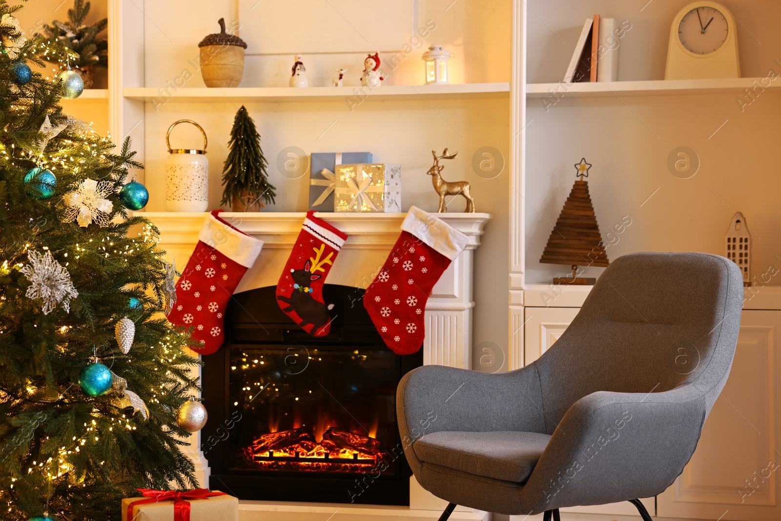 Photo of Christmas tree and armchair near decorated fireplace in room. Festive interior