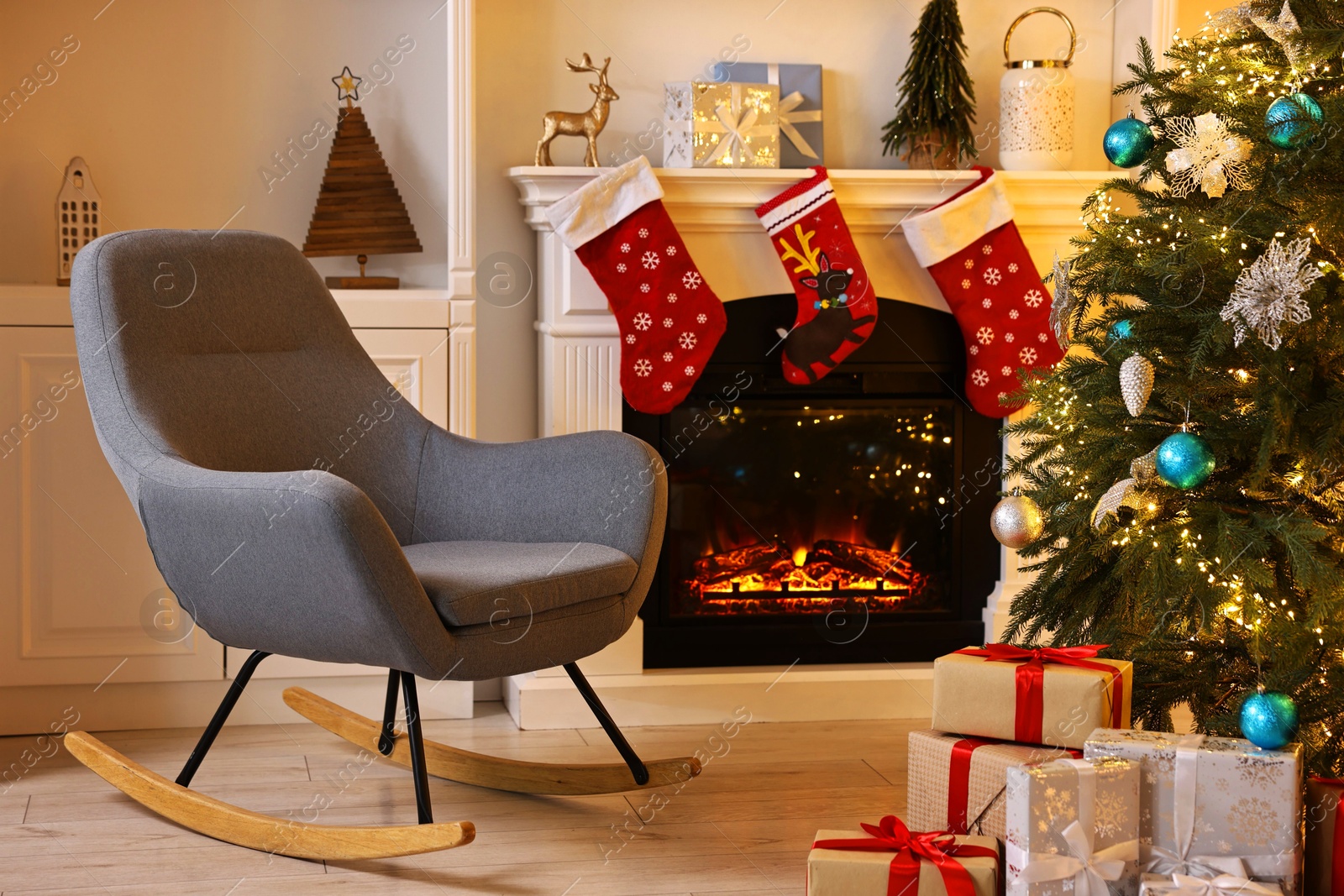 Photo of Christmas tree and rocking chair near decorated fireplace in room. Festive interior