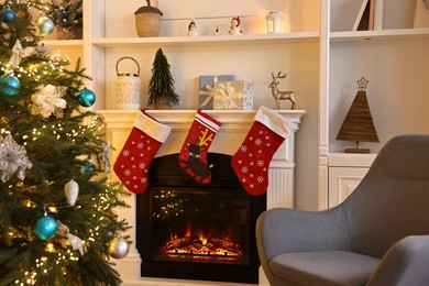 Photo of Christmas tree and armchair near decorated fireplace in room. Festive interior