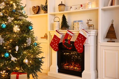 Photo of Christmas tree and decorated fireplace in room. Festive interior