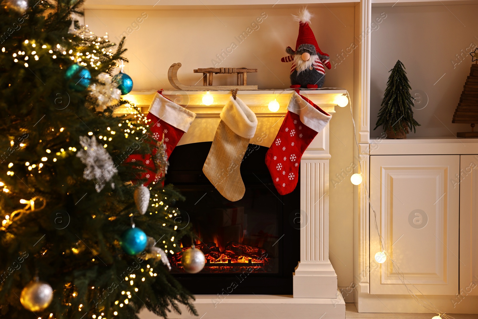 Photo of Christmas tree and decorated fireplace in room. Festive interior