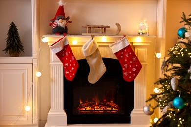 Photo of Decorated fireplace and Christmas tree in room. Festive interior