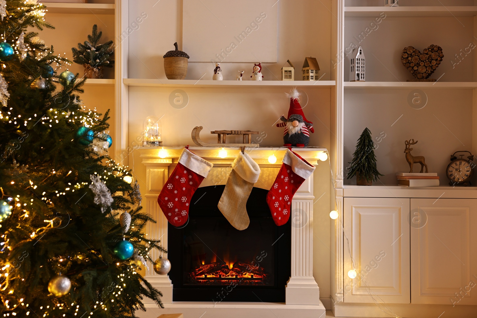 Photo of Christmas tree and decorated fireplace in room. Festive interior