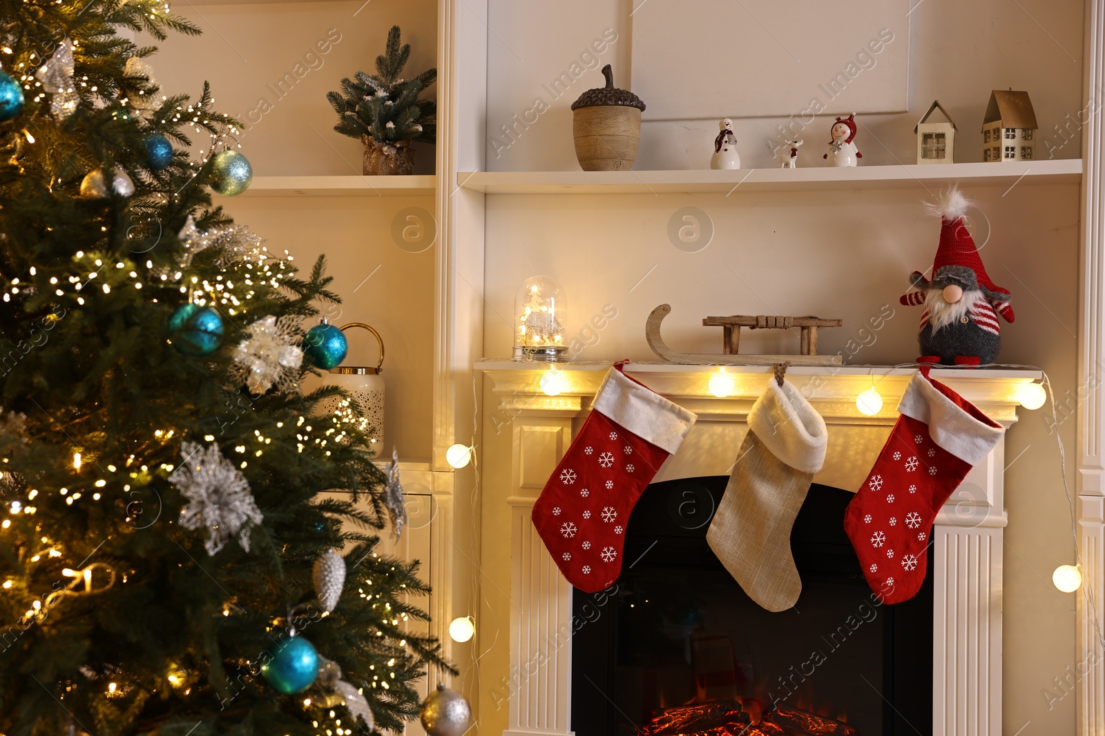 Photo of Christmas tree and decorated fireplace in room. Festive interior