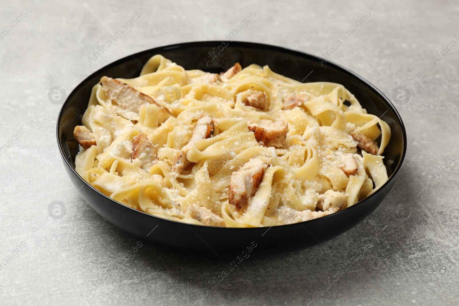 Photo of Tasty Alfredo pasta with chicken on light grey table