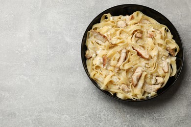 Photo of Tasty Alfredo pasta with chicken on light grey table, top view. Space for text