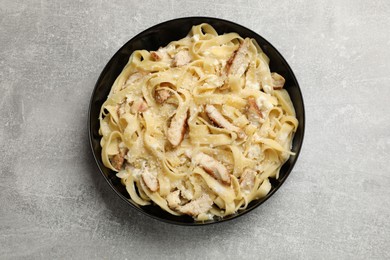 Photo of Tasty Alfredo pasta with chicken on light grey table, top view