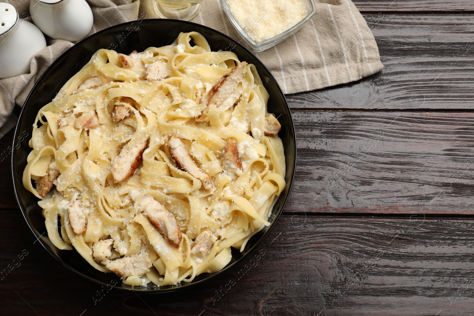 Photo of Tasty Alfredo pasta with chicken on wooden table, flat lay. Space for text