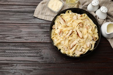 Photo of Tasty Alfredo pasta with chicken on wooden table, flat lay. Space for text