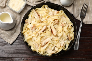 Photo of Tasty Alfredo pasta with chicken served on wooden table, flat lay