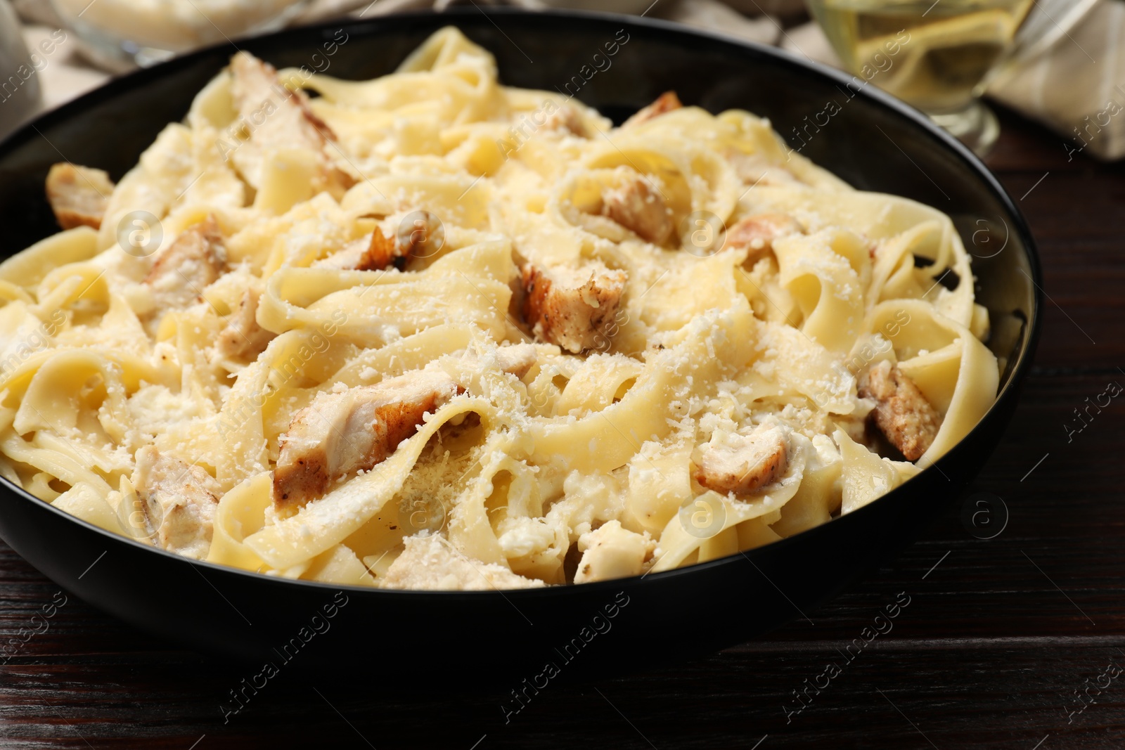 Photo of Tasty Alfredo pasta with chicken on wooden table, closeup