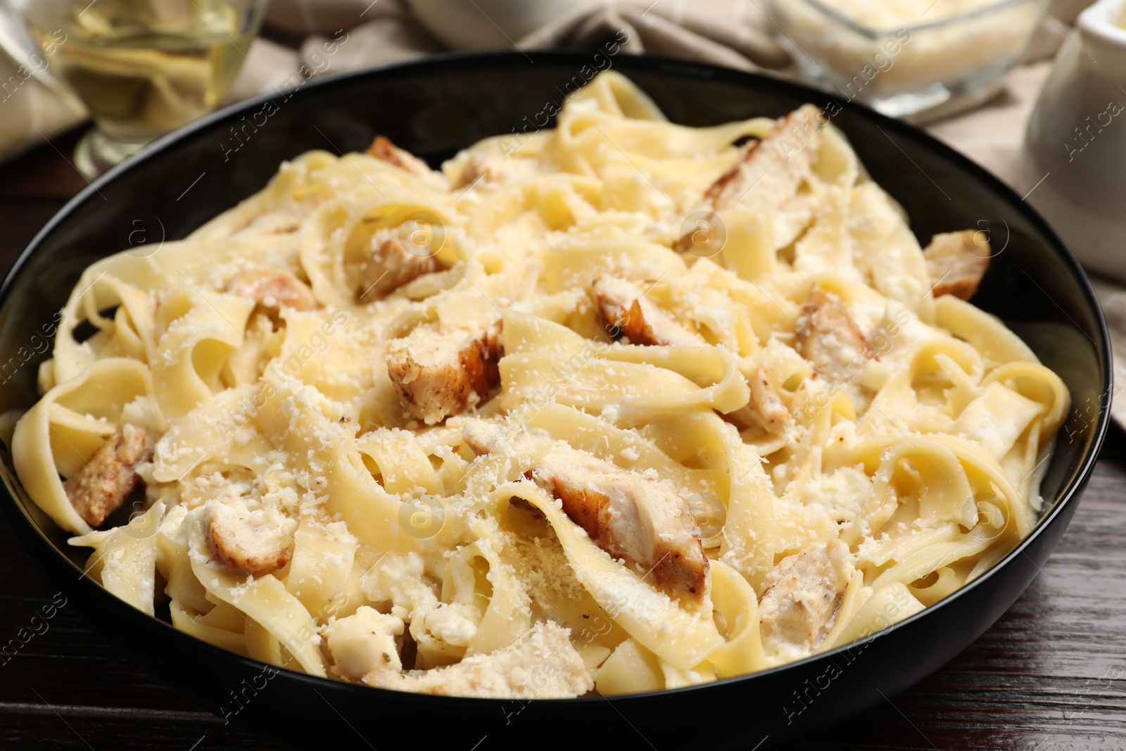 Photo of Tasty Alfredo pasta with chicken on wooden table, closeup