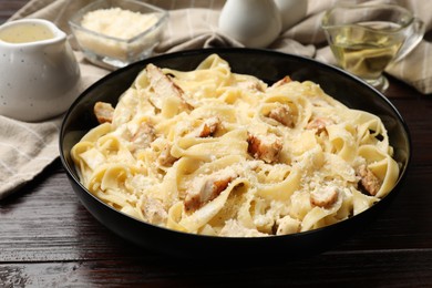 Photo of Tasty Alfredo pasta with chicken on wooden table