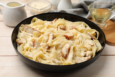 Photo of Tasty Alfredo pasta with chicken on light wooden table