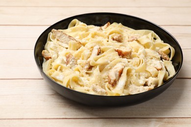 Photo of Tasty Alfredo pasta with chicken on light wooden table