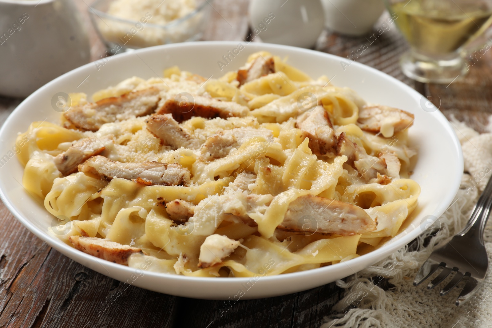 Photo of Tasty Alfredo pasta with chicken on wooden table, closeup