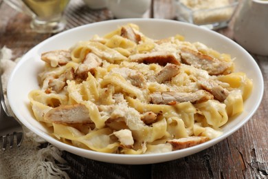 Photo of Tasty Alfredo pasta with chicken on wooden table, closeup