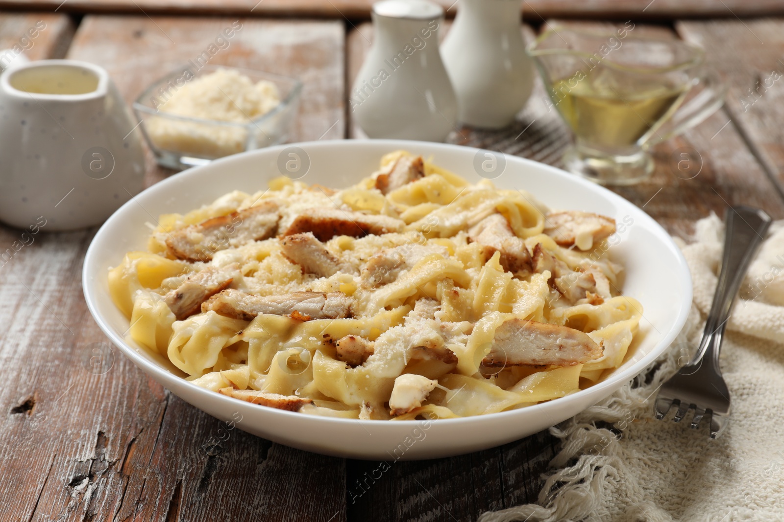 Photo of Tasty Alfredo pasta with chicken served on wooden table