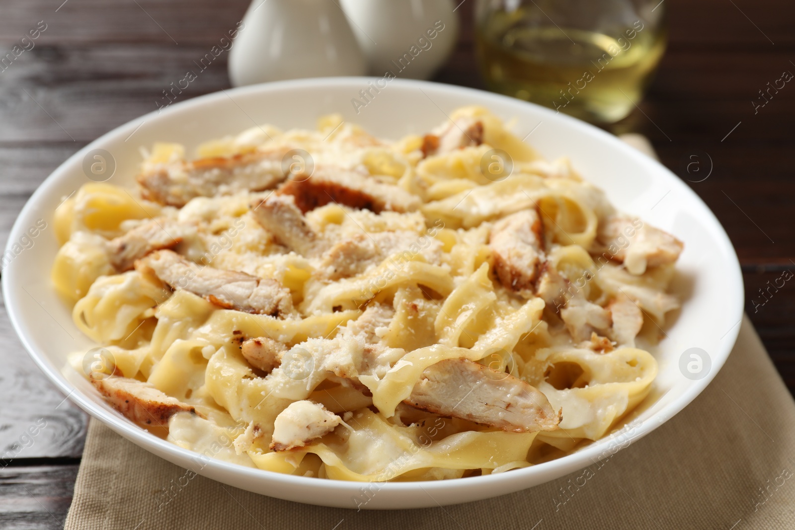 Photo of Tasty Alfredo pasta with chicken on wooden table, closeup