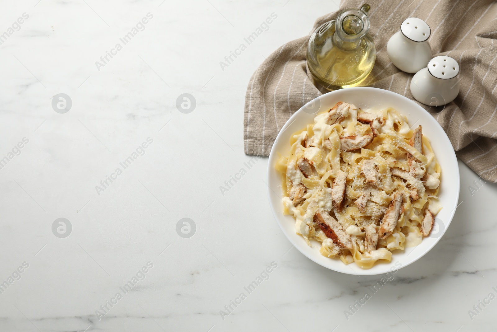 Photo of Tasty Alfredo pasta with chicken on white marble table, flat lay. Space for text