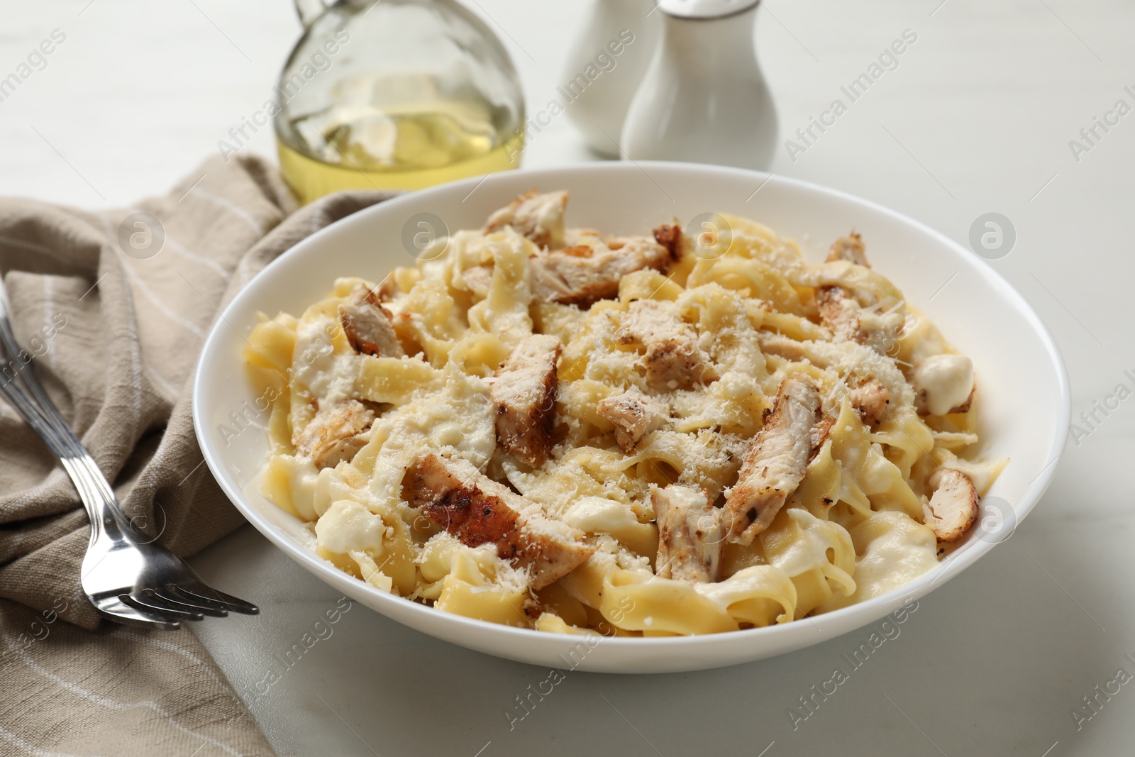 Photo of Tasty Alfredo pasta with chicken served on white marble table