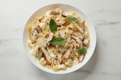 Photo of Tasty Alfredo pasta with chicken on white marble table, top view