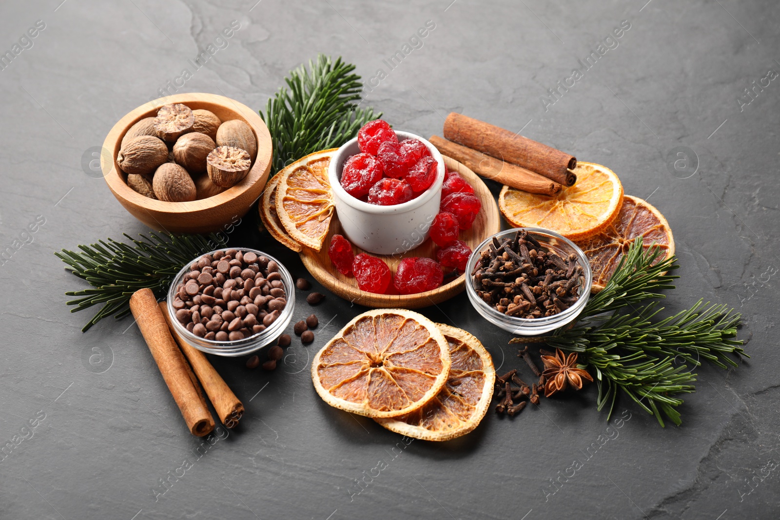 Photo of Different aromatic spices and fir tree branches on black table. Christmas season