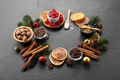 Photo of Different aromatic spices and fir tree branches on black table. Christmas season