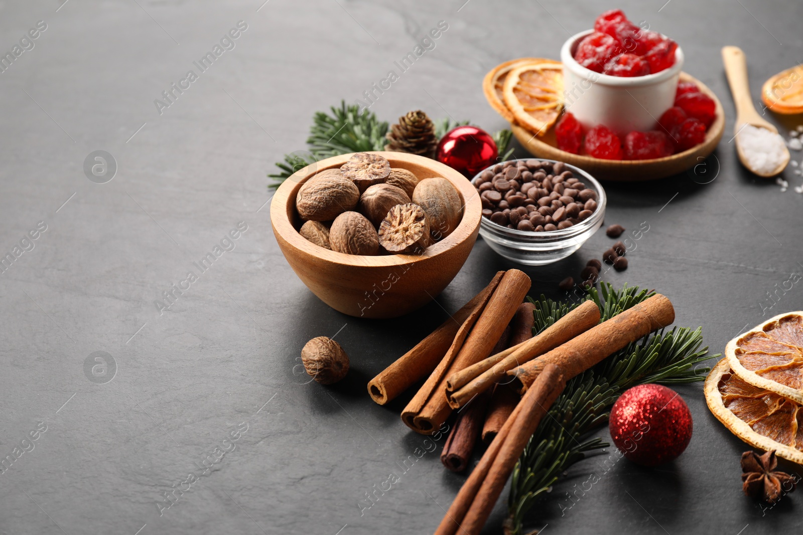 Photo of Different aromatic spices and fir tree branches on black table. Christmas season