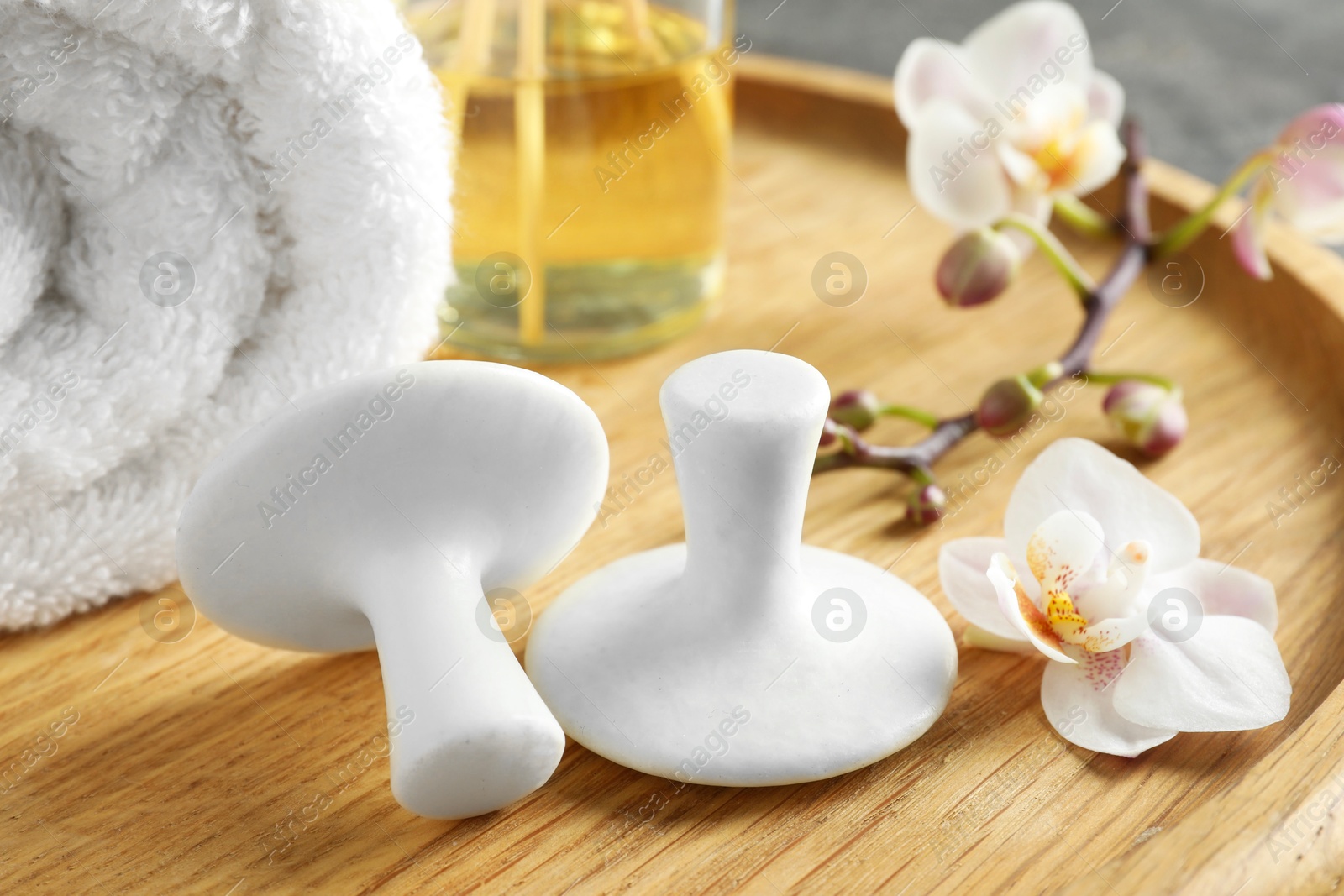 Photo of Spa stones, orchid flowers and towel on wooden tray, closeup