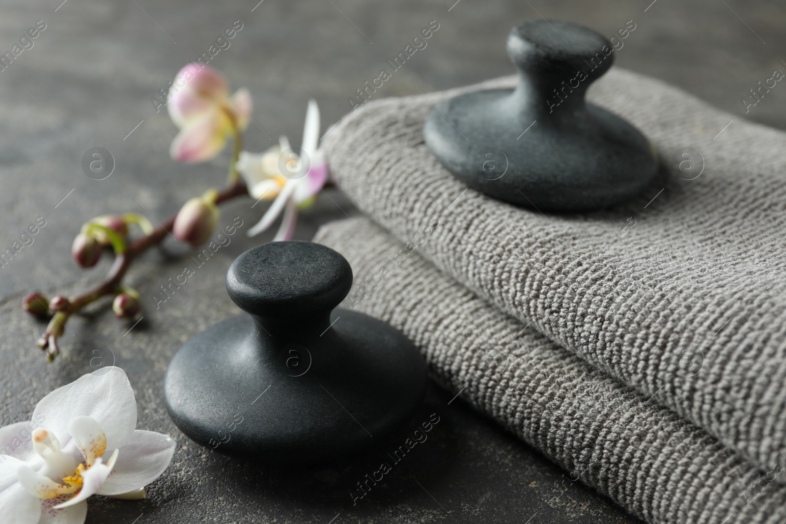 Photo of Spa stones, towels and orchid flowers on grey table, closeup