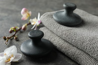 Spa stones, towels and orchid flowers on grey table, closeup