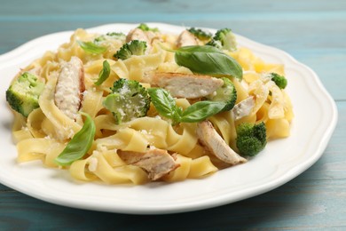 Photo of Delicious pasta Alfredo with chicken, cheese, broccoli and basil on light blue wooden table, closeup