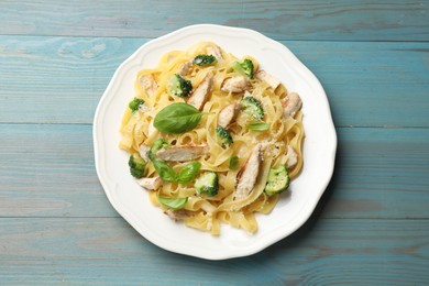 Photo of Delicious pasta Alfredo with chicken, cheese, broccoli and basil on light blue wooden table, top view