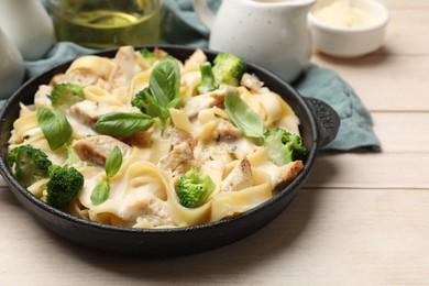 Photo of Delicious pasta Alfredo with chicken, cheese, creamy sauce, broccoli and basil on wooden table, closeup