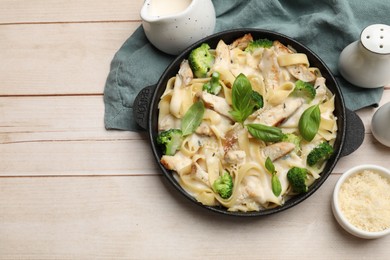 Photo of Delicious pasta Alfredo with chicken served on wooden table, flat lay. Space for text