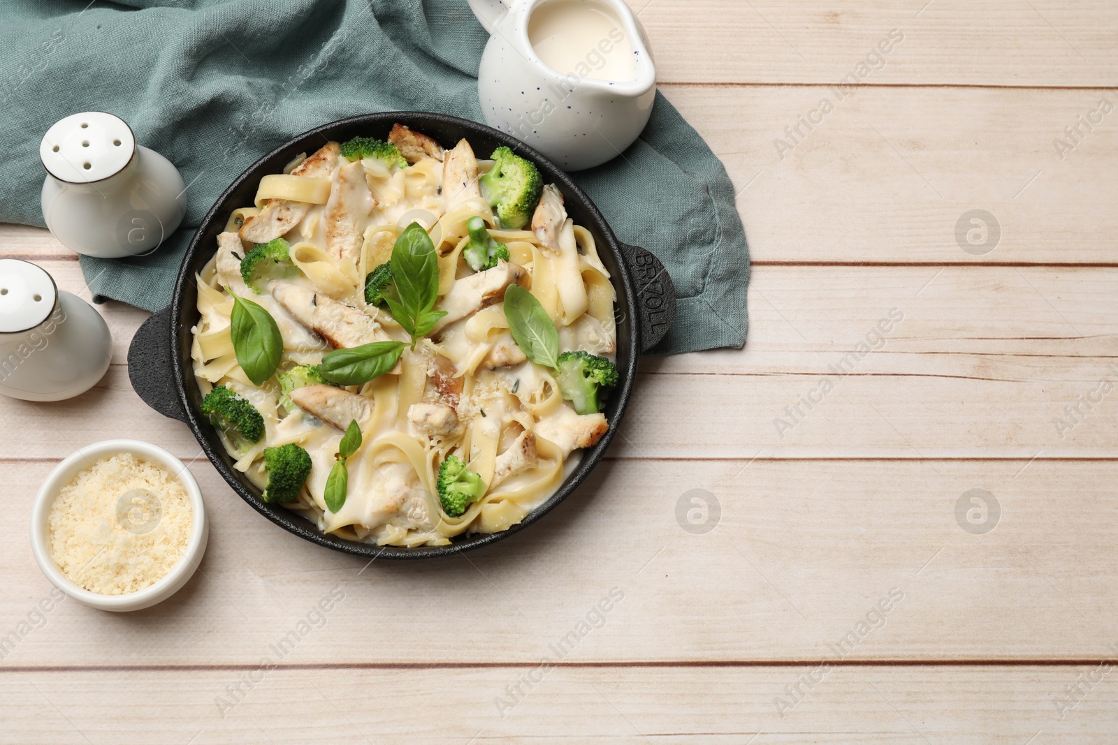 Photo of Delicious pasta Alfredo with chicken served on wooden table, flat lay. Space for text