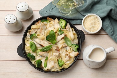 Photo of Delicious pasta Alfredo with chicken served on wooden table, flat lay