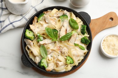 Photo of Delicious pasta Alfredo with chicken served on white marble table, flat lay