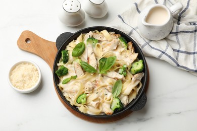 Photo of Delicious pasta Alfredo with chicken served on white marble table, flat lay