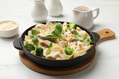 Photo of Delicious pasta Alfredo with chicken, cheese, creamy sauce, broccoli and basil on white marble table, closeup