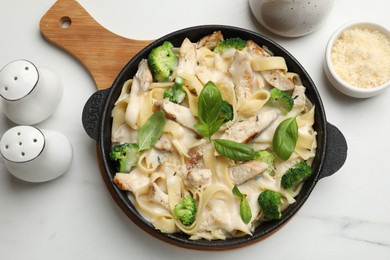 Photo of Delicious pasta Alfredo with chicken served on white marble table, flat lay