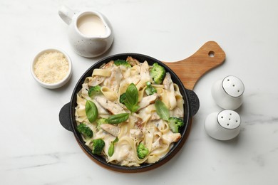 Photo of Delicious pasta Alfredo with chicken served on white marble table, flat lay