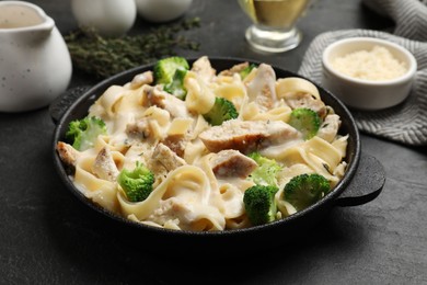 Photo of Delicious pasta Alfredo with chicken served on black table, closeup