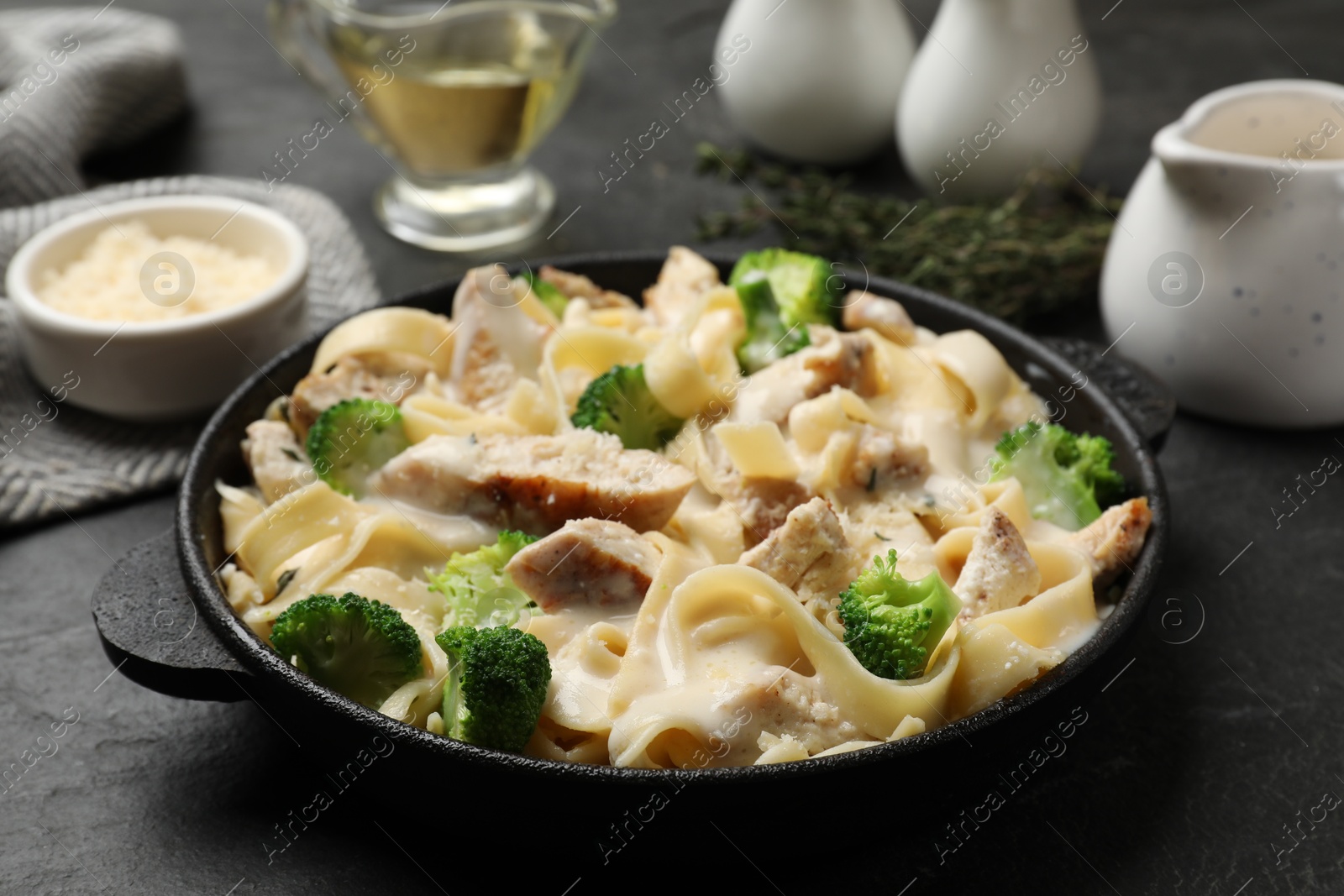 Photo of Delicious pasta Alfredo with chicken served on black table, closeup