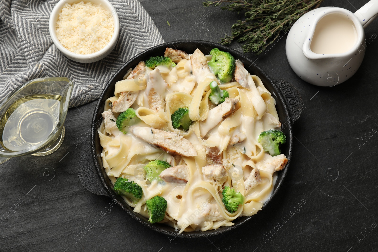 Photo of Delicious pasta Alfredo with chicken served on black table, flat lay