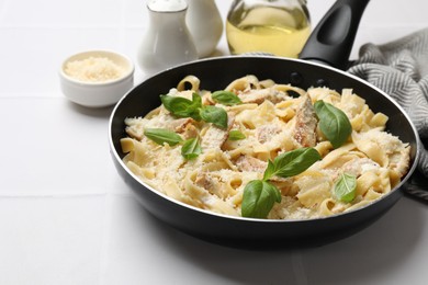 Photo of Delicious pasta Alfredo with chicken, cheese and basil on white tiled table, closeup