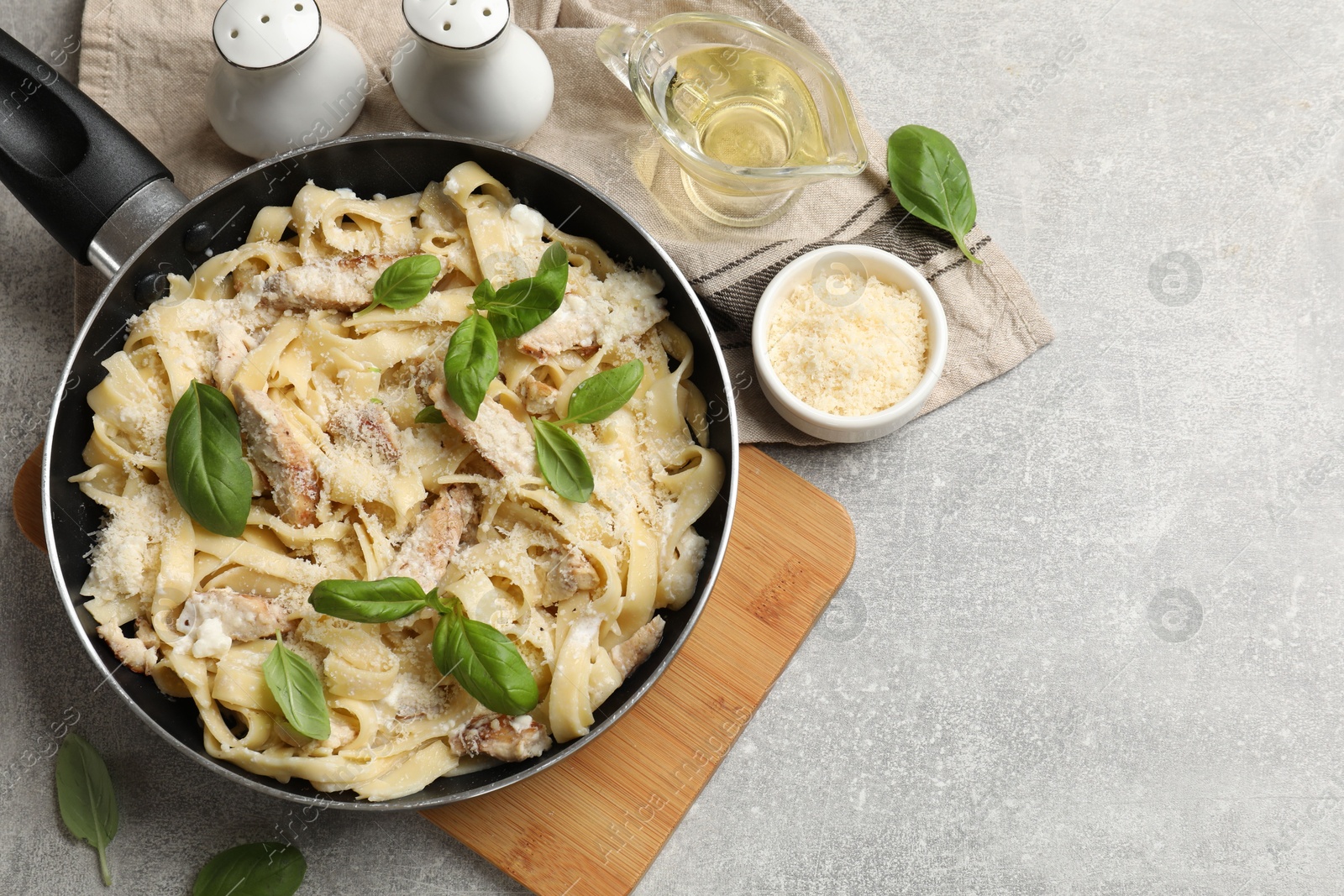 Photo of Delicious pasta Alfredo with chicken served on grey table, flat lay. Space for text