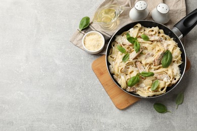 Photo of Delicious pasta Alfredo with chicken served on grey table, flat lay. Space for text