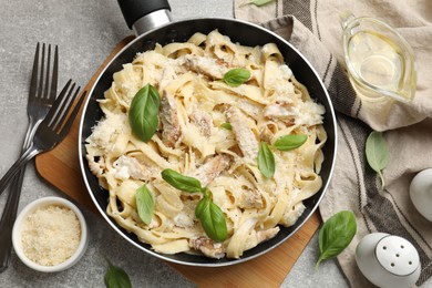 Photo of Delicious pasta Alfredo with chicken served on grey table, flat lay